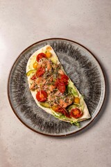 Delicious flatbread topped with smoked salmon and vegetables on plate