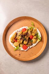 Delicious manti dumplings are served on a plate with sour cream and herbs