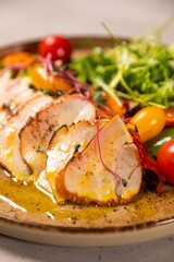 Sliced grilled chicken breast served on plate with fresh salad and mustard sauce