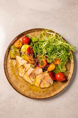 Sliced grilled chicken breast served with grilled vegetables and fresh salad