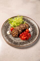 Grilled meatballs served with roasted red peppers and frisee salad on plate