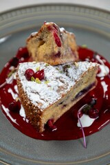 Delicious cranberry cake lying on berry sauce and plate