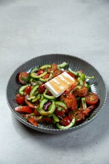 Greek salad with grilled feta cheese, cucumber and tomato in a bowl