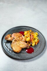 Roasted chicken tabaka with potatoes and herbs on gray plate