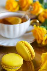 On the white table there is hot tea, cakes and delicate roses.