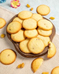 Delicious round cookies with raisins on wooden board on beige textured background