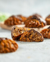 Delicious homemade fig and nut cookies covered in chocolate laying on white table