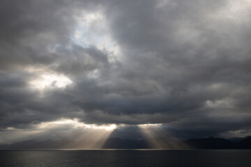 Storm clouds over the sea with strong rays of light cascading towards the water