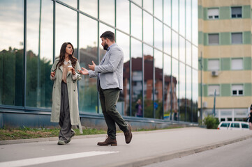 Businessman explaining something to businesswoman while walking on the street