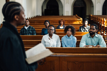 African american priest leading congregation in prayer at church