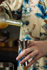 Close-up of bartender pouring juice into a jigger from a bottle