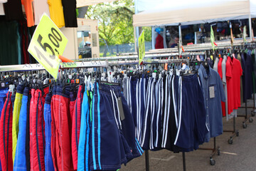 colorful Array of Clothing Hanging on Racks at a Busy Market Stall and price