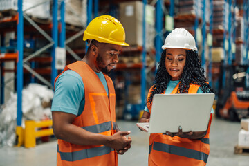 Warehouse workers using laptop checking inventory in logistics center