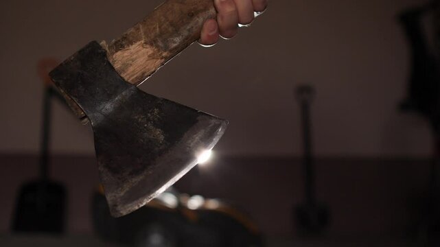 close up of man holding old axe in garage with tools stored