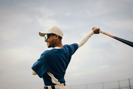Baseball player in blue uniform preparing for a game with a confident smile on a sunny day