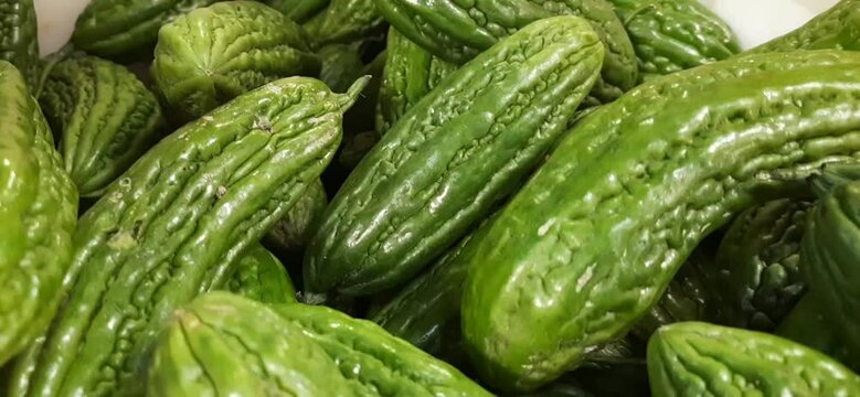 Pile of green bitter gourd or paria or pare vegetable background. Ready sold in traditional market Indonesia