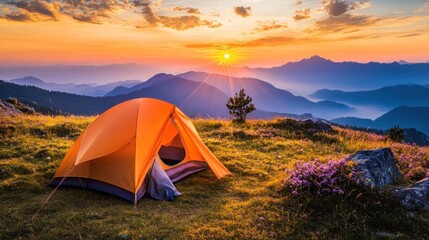 A lone orange tent sits atop a mountain ridge at sunset, with a panoramic view of the majestic mountain range in the background.