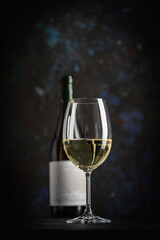 A dark, elegant still life of white wine in a glass with wooden background. Perfect for wine-themed...