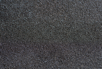 Detailed close-up of a rough black sandpaper texture, ideal for backgrounds, construction, or industrial themes.