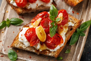 Cottage cheese and roasted tomatoes sourdough bread toast on a wooden board.