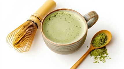 A cup of frothy matcha green tea latte in a ceramic cup, with a bamboo whisk and matcha powder nearby, all on a pristine white background.