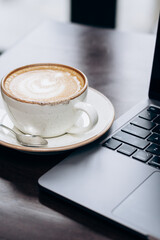 A laptop and a cup of coffee on the table. Office workday