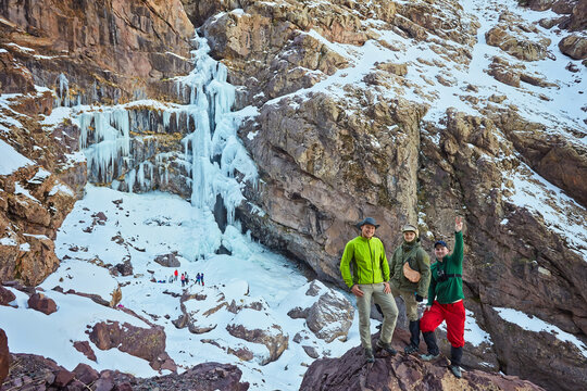 group of travelers near a frozen Waterfall near Jebel Toubkal peak, Atlas mountains, Morocco