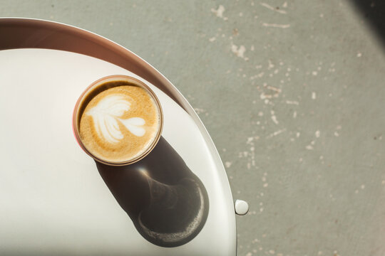 Cappuccino cup with beautiful latte art on white table in cafe or coffee shop. Hot tasty drink in glass takeaway mug. take your coffee to go. eco friendly, plastic free, zero waste concept. flat lay