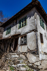 Abandoned houses and other buildings, lit by sunlight, street view, Pirin village and mountain, Bulgaria