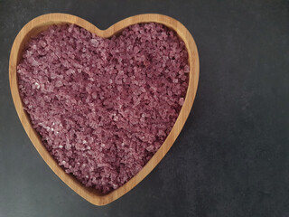 Wine salt crystals in a heart shaped bowl on black background
