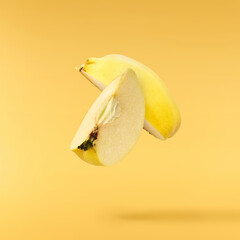 Fresh ripe yellow Quince fruit  falling in the air isolated on yellow background. Food levitation...
