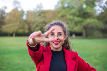 fröhliche junge Frau zeigt victory - Zeichen im herbstlichen Park