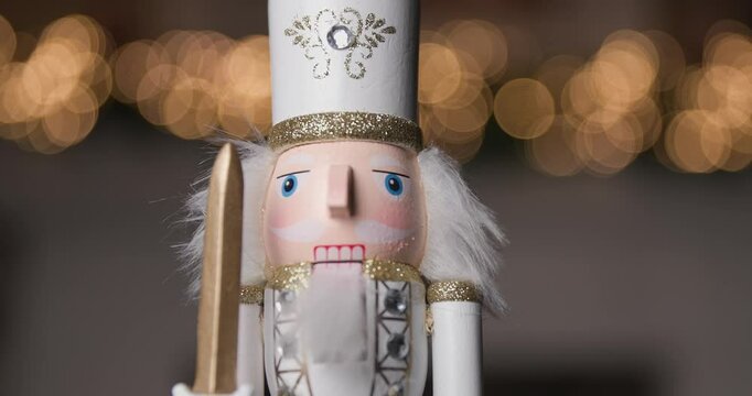 spinning Nutcracker in a white uniform with a sword, representing the Christmas joy while being framed by the glowing beauty of golden bokeh lights