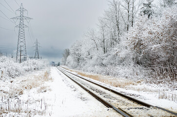 Train tracks leading off into a snowy, frozen landscape with hydro towers alongside the tracks