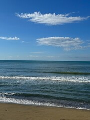 Blue ocean, sky with clouds, sandy beach.