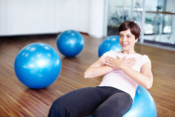 Fototapeta premium Fitness, happy woman and exercise ball with sit up for core, abdomen and balance with workout at gym. Wellness, training and health club with athlete and stretching with pilates and sport gear