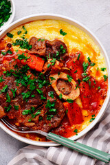 Stewed in osso bucco sauce with vegetables and cheese polenta in a bowl.style huggr