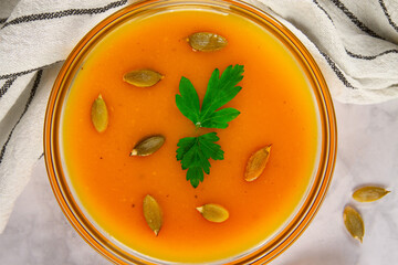 Close-up top view of delightful pumpkin soup garnished with pumpkin seeds and greens.