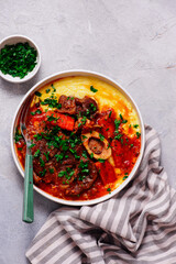 Stewed in osso bucco sauce with vegetables and cheese polenta in a bowl.style huggr