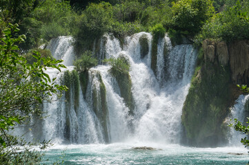 Waterfall among the green summer forest.