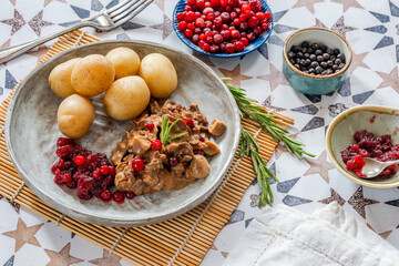 Traditional Norwegian reindeer stew with lingonberries and boiled potatoes