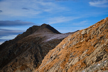 A stunning panoramic view of mountain peaks under a clear blue sky. The rugged terrain and dramatic scenery offer a sense of adventure and exploration. Fagaras mountains, Romania
