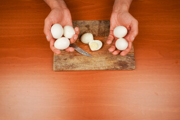 Board with boiled chicken eggs on table, closeup. Healthy food. Protein. Sportsmen's food. Preparing food. Horizontal photo. Vegetarian. Man holding chicken eggs over wooden board. Boiled eggs.