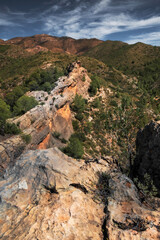 landscape of Rocky Cliffside Path Overlooking Lush Green Valley with Expansive Sky View