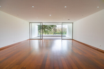 amplia sala de departamento vacio con piso de madera