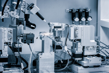 A machine with a lot of wires and tubes is in the middle of a room. The machine is surrounded by other machines and wires. The room is filled with a sense of technology and innovation