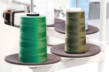 Spool of thread on an industrial sewing machine in a garment factory, industrial textile background, sewing factory, clothing manufacturing