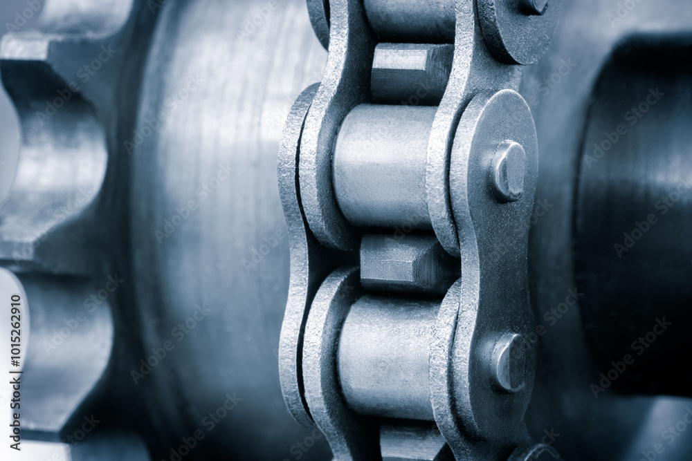 Poster A chain is shown in a close up. The chain is made of metal and has a silver color. The chain is connected to a gear and is in motion. Concept of movement and mechanical energy