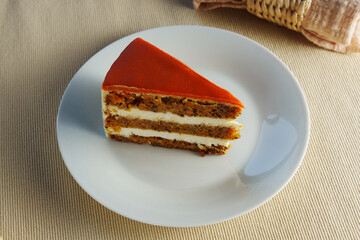 A slice of moist carrot cake reveals layers of rich cream cheese frosting nestled between spiced cake, perfect for dessert lovers enjoying a sweet treat.