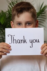 Teenager boy holding a white card with the words "thank you" © Gosia